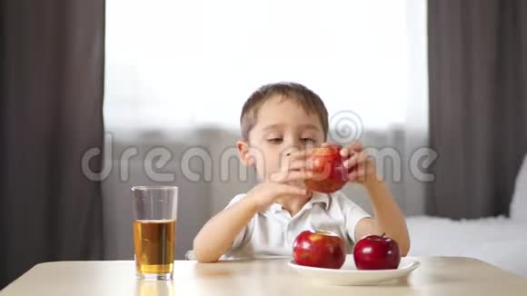 快乐的孩子正在喝苹果汁吃苹果坐在房间的一张桌子旁儿童食物生态上视频的预览图