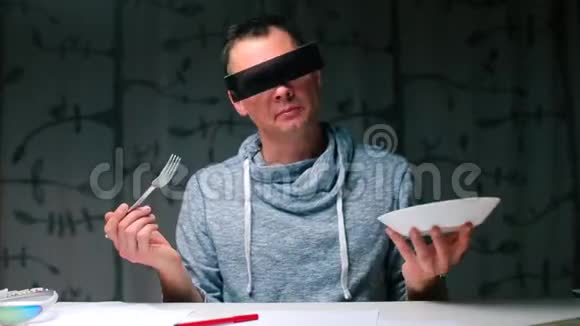一个戴黑眼镜的人从一个白色盘子里在桌子旁吃东西视频的预览图