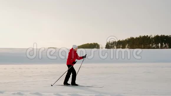 一个穿红色夹克的女人正在结冰的湖面上滑雪冬季滑雪视频的预览图