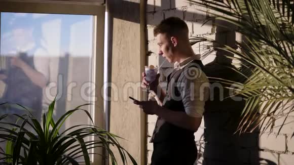 商人在他的时尚公寓风格的阁楼一个年轻人拿着智能手机和视频的预览图