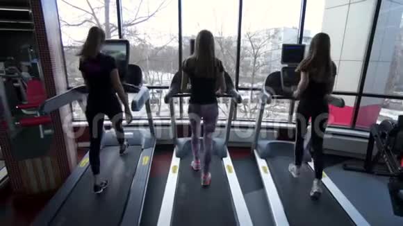 三位年轻女性在跑步机上行走的后景视频的预览图