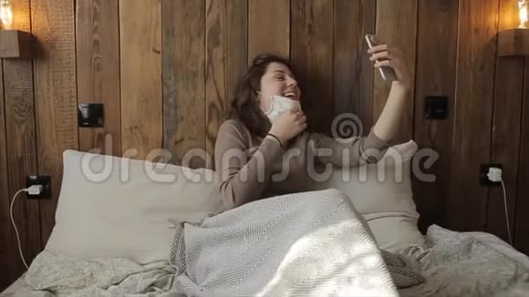 一个漂亮的戴着面具的女孩在检疫期间在家里打电话冠状病毒COVID19视频的预览图