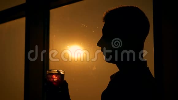 一个人在日落时喝鸡尾酒窗的背景中视频的预览图
