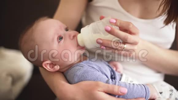 妈妈抱着4个月大的小男孩用奶瓶喂他牛奶视频的预览图