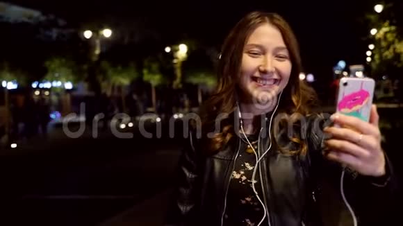 晚上在街上使用手机耳机的年轻女孩慢动作视频的预览图