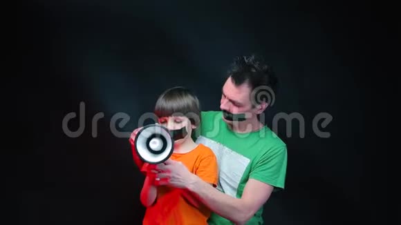 一个男人和一个孩子用嘴粘着抗议对着扩音器大喊大叫视频的预览图