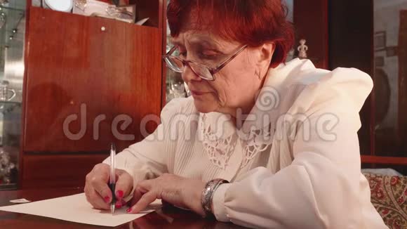 戴眼镜的老太太和白布尔斯在一张纸上写了一封信视频的预览图