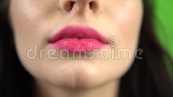 女孩把粉红色的泡泡放在嘴上嚼口香糖4k特写粉红色的嘴唇绿色的屏幕视频的预览图