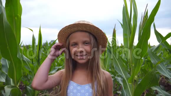 一幅迷人的小女孩对着镜头在玉米的背景下把草帽拉直视频的预览图