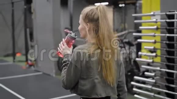一个年轻漂亮的女人在健身房完成了她的教练金发女孩去喝水视频的预览图