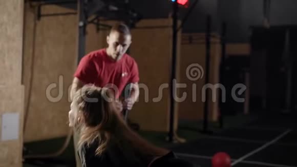 教练在健身房一名男子向两名年轻妇女展示锻炼金发女郎学会正确的锻炼技巧视频的预览图