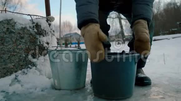 一个冬天有水桶的老人从井里提水视频的预览图