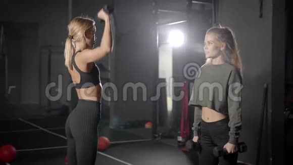 健身房里有两个漂亮的金发女郎女孩用轻体重进行练习重要的是要监测健康和视频的预览图