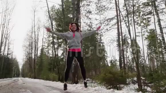 女人做跳跃千斤顶作为在森林中锻炼新鲜空气低角度视角和慢运动视频的预览图