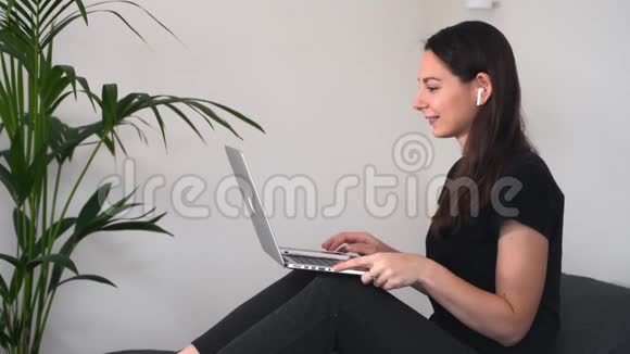 年轻女子坐在家里手提电脑和无线耳机并有视频聊天在线教育视频的预览图