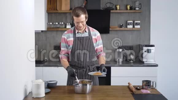 年轻漂亮的厨师是厨房里的男人糖果师把面团的原料混合在圆规中这就是视频的预览图
