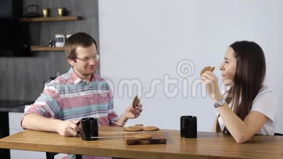 这对夫妇休息一下喝茶和吃饼干愉快的夫妻坐在厨房里交流视频的预览图