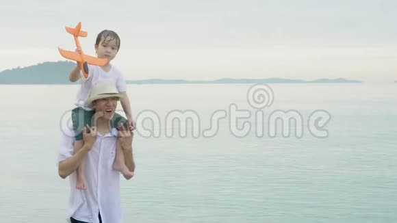快乐的亚洲家庭与父子两人在海滩上挽着飞机玩得开心快乐视频的预览图