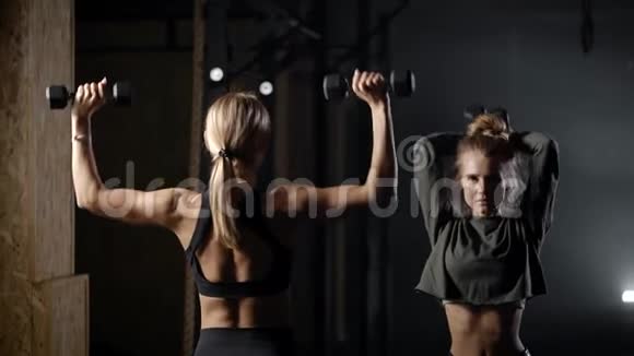 健身房里有两个漂亮的金发女郎女孩用轻体重进行练习重要的是要监测健康和视频的预览图