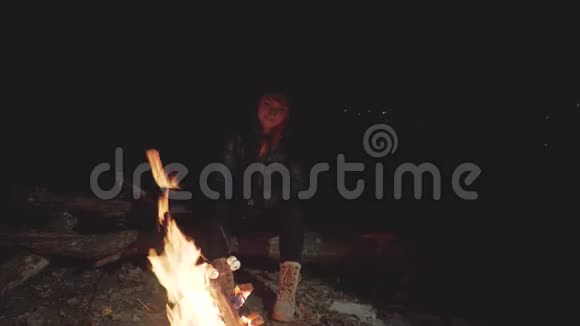 一个女孩晚上围着火炉坐着烤棉花糖视频的预览图
