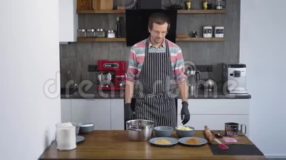 年轻漂亮的厨师是厨房里的男人糖果师把面团的原料混合在圆规中这就是视频的预览图