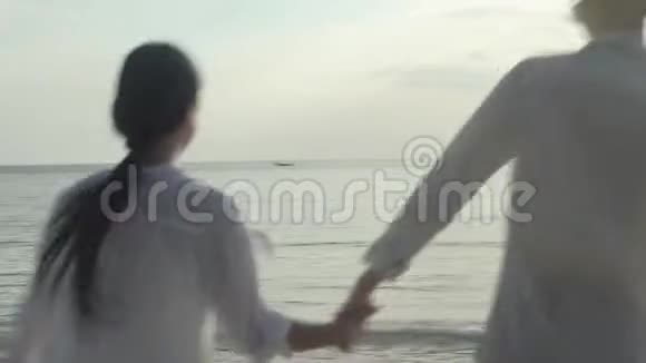 快乐的亚洲情侣一起在夏天的海滩上牵着手拥抱浪漫视频的预览图