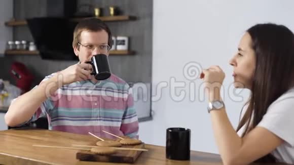 这对夫妇休息一下喝茶和吃饼干愉快的夫妻坐在厨房里交流视频的预览图
