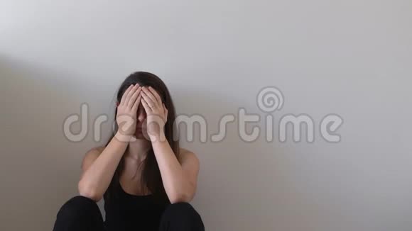 抑郁的年轻女子孤独的人坐在靠近墙壁的地板上视频的预览图