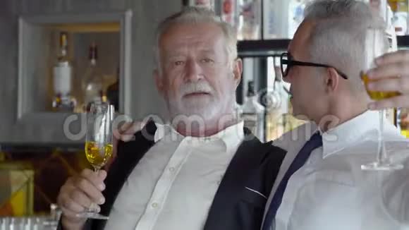 两位资深商人在酒吧成功地喝饮料并举行庆祝活动视频的预览图