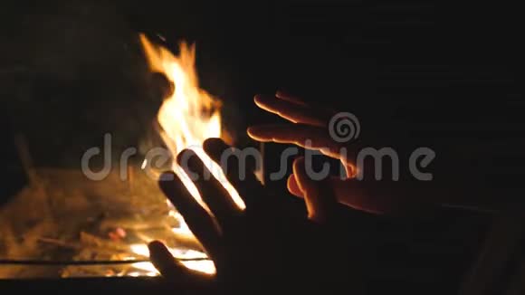 男性游客在黑色背景下用金属燃烧的火焰温暖他的手臂年轻人在前面搓手视频的预览图