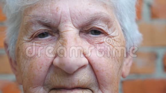 老年妇女的肖像白发看着镜头布满皱纹的女性脸上有严肃的表情视频的预览图