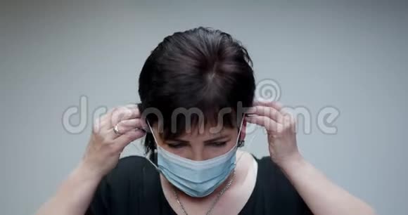 肖像高级妇女参加医疗面具深呼吸看着灰色背景上的相机保健和保健视频的预览图