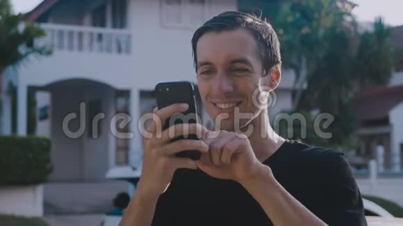 快乐的微笑男子滚动智能手机在城市街头背景视频的预览图
