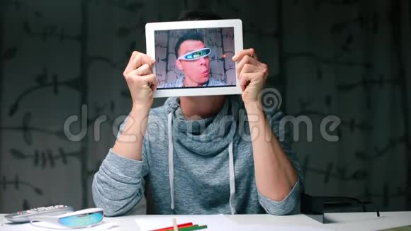 疯狂的家伙坐在桌子旁拿着一块平板电脑拿着相机屏幕视频的预览图