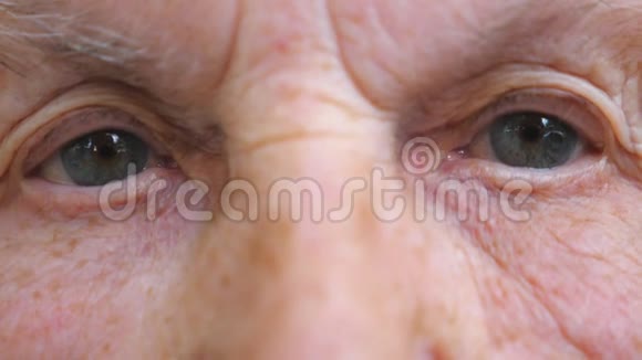 老年妇女在镜头中观看沉思的肖像布满皱纹的女性脸奶奶的脸很平静视频的预览图