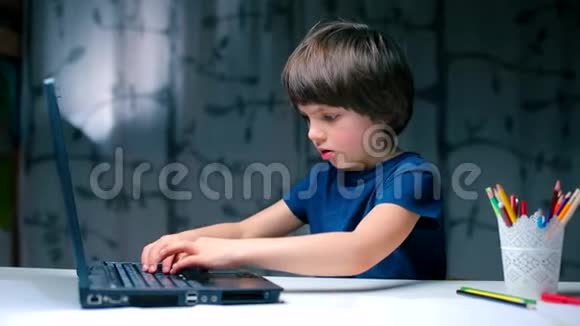 坐在桌边的男孩随机地按键盘键视频的预览图