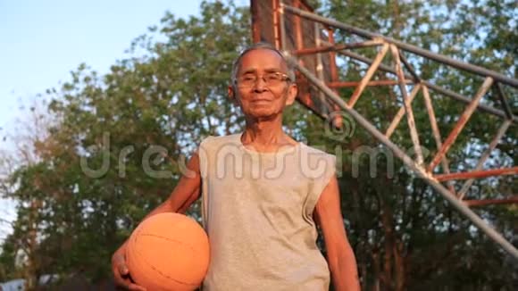 自信的亚洲老人穿着运动服夏天在户外篮球场上拿着篮球健康的生活方式和方式视频的预览图