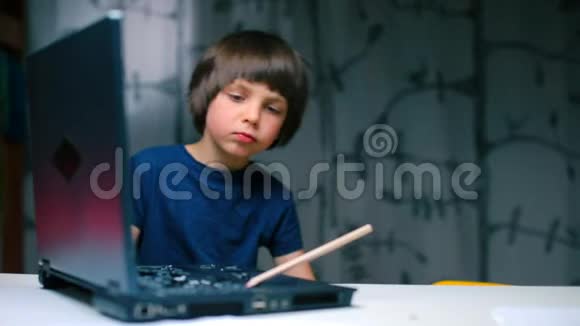 这个男孩坐在一张带着笔记本电脑的桌子旁用铅笔把钥匙弄坏了视频的预览图