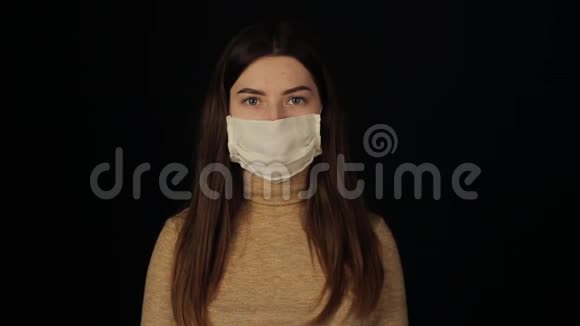 女孩环顾四周摘下一个保护面具看着相机冠状病毒COVID19孤立的黑色视频的预览图