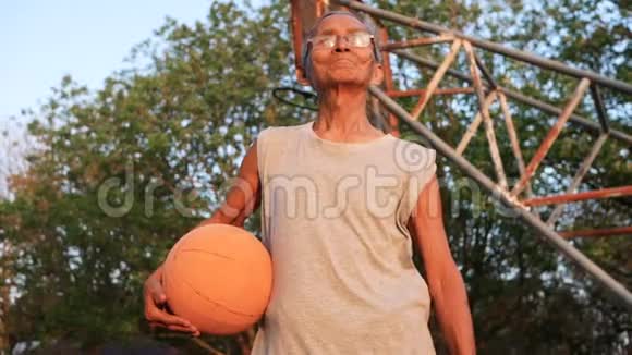 自信的亚洲老人穿着运动服夏天在户外篮球场上拿着篮球健康的生活方式和方式视频的预览图
