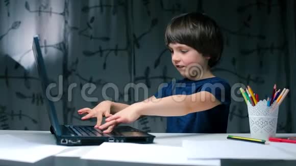 一个男孩坐在桌子旁在笔记本电脑上打字的肖像视频的预览图