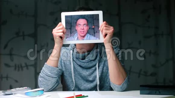 平板屏幕上一个惊讶的男人的脸视频的预览图