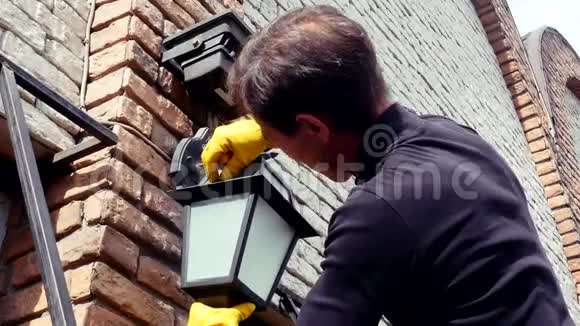 电工用乳胶手套将经典灯泡安装到户外灯笼中视频的预览图