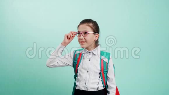 一个戴着蓝色背景眼镜的女学生的肖像一个穿着白色衬衫背着背包的年轻女孩视频的预览图