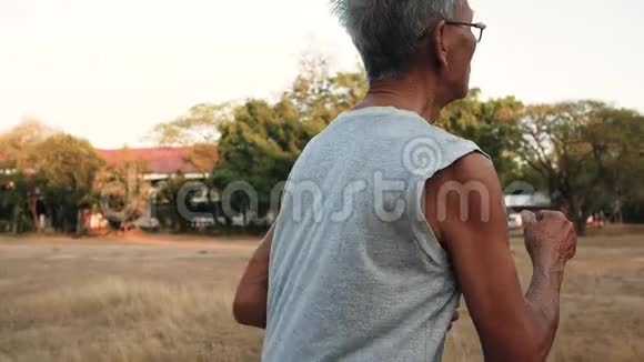 在日落的天空背景下亚洲老人在公园里慢跑健康的生活方式和保健理念视频的预览图