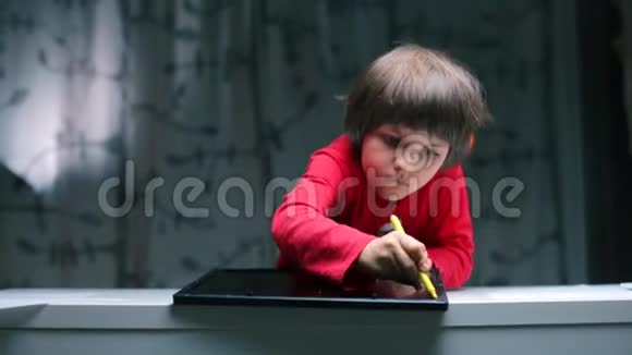 一个坐在桌子旁的男孩用铅笔画键盘和平板电脑视频的预览图