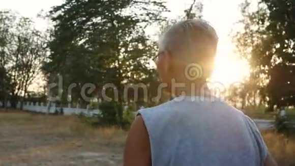 在日落的天空背景下亚洲老人在公园里慢跑健康的生活方式和保健理念视频的预览图