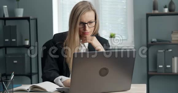 专注的女商人坐在桌旁手提电脑视频的预览图