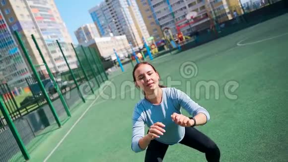 那个女孩在街道上的一个围栏地区参加体育活动街头健身操蹲着跳起来这就是视频的预览图