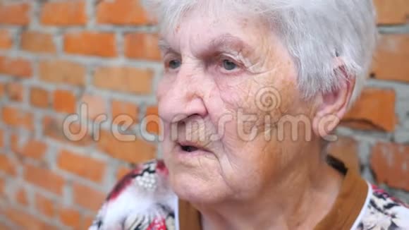 祖母坐在户外和别人说话老年妇女面部表情严肃的肖像视频的预览图